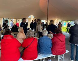 Nieuwe bewoners en belangstellenden luisteren naar de toespraak tijdens het opleverfeest van de Ankerplaats in Muiden