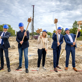 5 samenwerkende partijen met een hamer in de hand om de laatste heipaal de grond in te slaan op circusterrein
