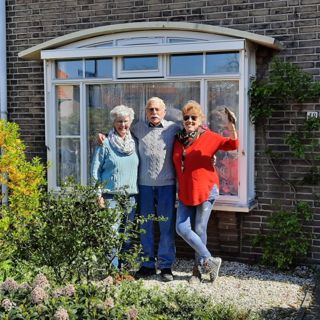 2 dames en een heer voor een huis