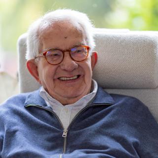 Oudere man lachend in stoel